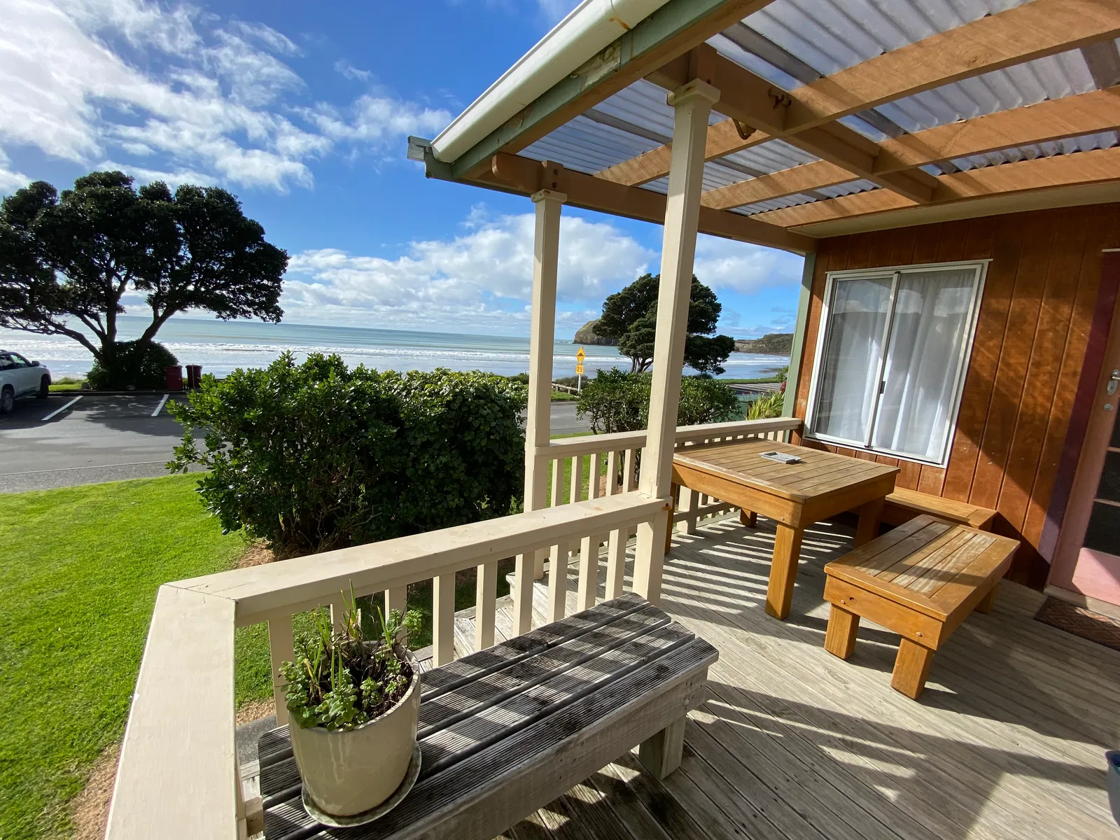 Bach A’s sunny timber deck, with a wooden table, outdoor chairs and the sea beyond Bach A’s sunny timber deck, with a wooden table, outdoor chairs and the sea beyond